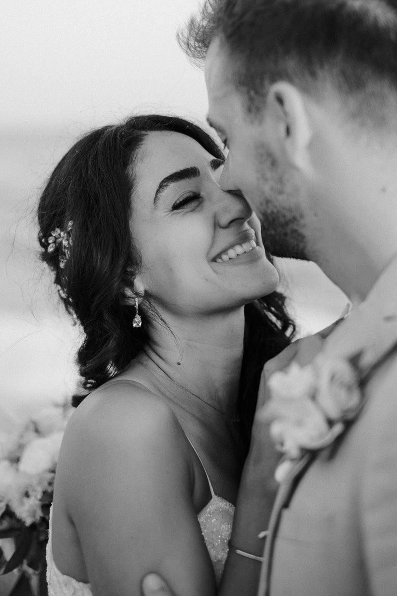 newly married couple kissing on the beach in tenerife and laughing 
