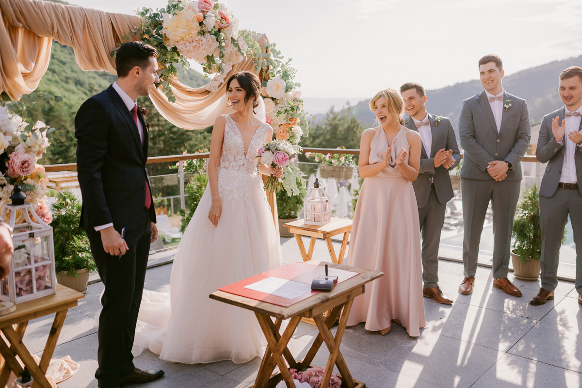 bride and groom with their guests laughing during their wedding ceremony in a beautiful setting